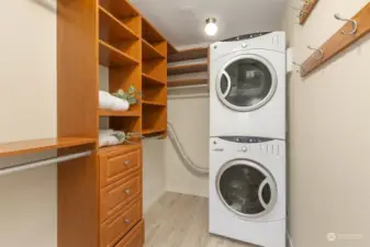 Primary Bedroom with updated carpeting, wall sconces, and a walk-in closet with vinyl flooring smartly installed.  Stackable GE white washer and dryer located in walk-in closet.  A well thought out California closet designed storage system to stay neat.