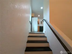 Stair case enters the kitchen area.