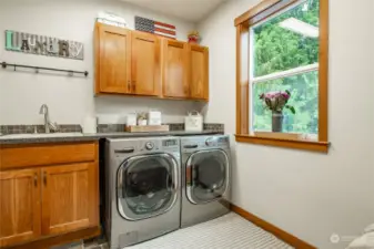 Laundry room between kitchen and garage.  Bench & shelving on opposite side of room.