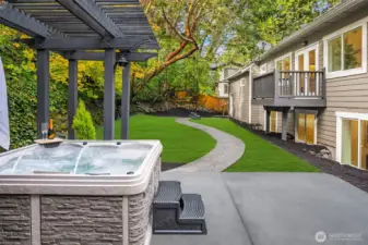 Hot tub showing fully fenced backyard and private balcony off main floor primary.