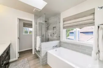 Spa-inspired primary bath features large subway tile, a frameless glass shower, and a deep soaking tub for ultimate relaxation