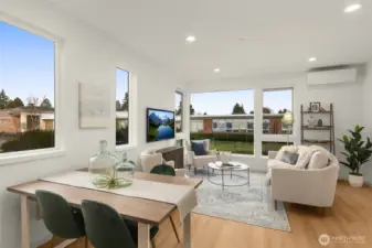 Expansive windows wrap the living room in sunlight, highlighting the home’s clean finishes and airy proportions.