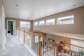 Upper hallway overlooks entry living & dining & illuminated vie natural light