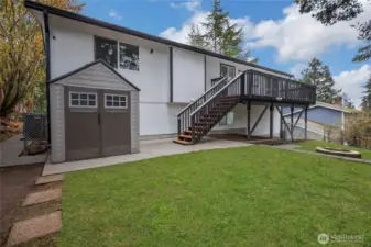 Back of home, showing one of two storage sheds, heat pump/ac on left side of home. Deck steps are new, decking on top is Trex material. Yard is fully fenced. (Note that yard/green was virtually enhanced)