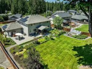 A backyard oasis featuring $180K in outdoor design - covered patio, hardscaping, gas fireplace, greenhouse, solar panels & power wall.