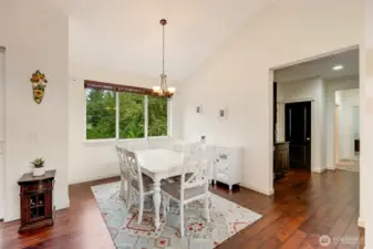 Adjacent to the living room, a formal dining area is highlighted by a stylish chandelier and a large window that fills the space with natural light, making it perfect for entertaining or intimate family meals.