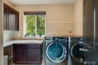 The utility room is equipped with a large, side-by-side front-loading washer and dryer, plenty of cabinets, a sink, and generous counter space—making laundry and household tasks effortless.