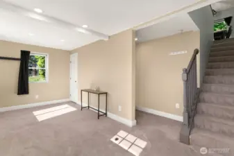Light-filled lower-level space with fresh carpet, recessed lighting, and direct access to the upper floor.