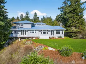 Stunning custom home with a striking metal roof, expansive windows, and beautifully landscaped grounds, perfectly positioned to capture serene views and a peaceful Northwest setting.