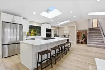 Remodeled kitchen with quartz island, skylights, abundant storage, and seamless connection to dining and living spaces.