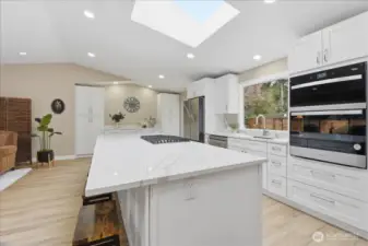 Beautifully remodeled kitchen with oversized quartz island, double ovens, and abundant prep space. Sliding glass door leads to backyard.