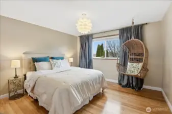 Bright and spacious guest bedroom with hardwood floors and a comfortable, versatile layout.