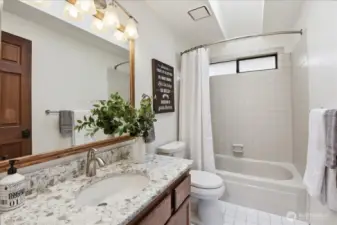 Well-kept guest bath with quartz vanity, tile floors, and a bright, functional layout
