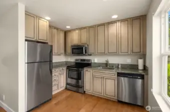 Apartment living space with complete kitchen with stainless steel appliances and washer and dryer