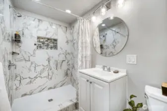 Beautiful tiled, walk-in shower with decorative niche and elegant marble-style surround.