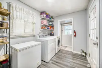 Dedicated laundry space with washer, dryer, and storage shelving.