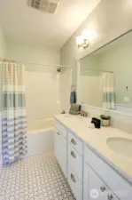 Another bath with a double quartz vanity with lots of storage and tiled floor.