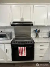 Stove has front operating dials and stainless steel backsplash.