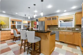 Kitchen features solid wood custom cabinetry, solid countertops, and stainless steel appliances. Toli custom flooring. Designer lighting above the island and eating nook.