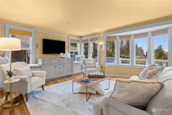 Living room features a bay window, custom molding and built in cabinets with benches.