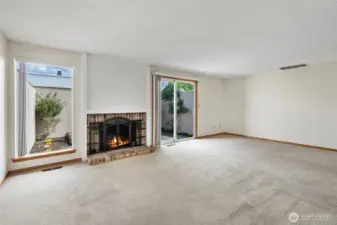 Spacious living room with wood burning fireplace and courtyard access
