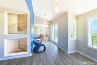 Stairwell cutout draws daylight to the central staircase. South facing hall with French doors to deck, connects living and dining/kitchen areas.