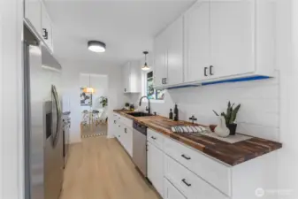 Kitchen features butcher block countertops, new full height cabinets, and new stainless appliances