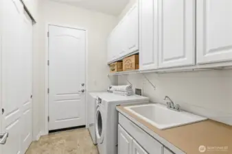 Laundry room with a double storage closet, laundry sink and lots of cabinets.