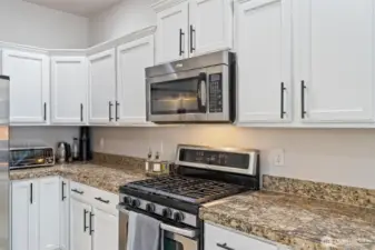 Updated kitchen with white cabinets and black handles, granite counter tops