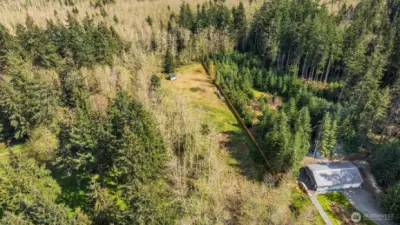 This is a view of the property that shows the cleared building area, the fence line and the neighbor that shares the driveway off the Highway.