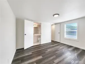 Wide angle view of primary bedroom with attached full bath and walk in closet
