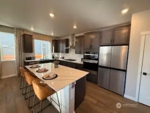 Beautiful modern open concept kitchen with upgraded appliances and gourmet configuration with stainless steel range hood.
