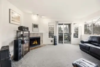 Spacious living room with lots of windows, a slider to the covered porch and a cozy wood burning fireplace.