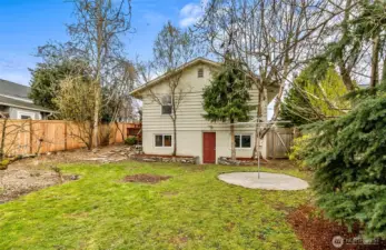 View of the back of the home, showing new fence, garden and all the fruit trees. This fully fenced back yard is perfect with the established landscaping