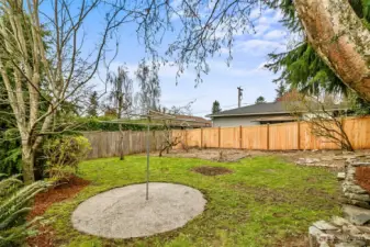 Side view of back yard including this handy concrete based clothes line and established flower beds