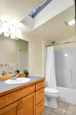 Upper-level full bathroom featuring a skylight that fills the space with natural light.