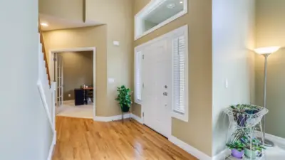 Sunlit entry featuring hardwood flooring throughout entry, kitchen and hallway accenting the painted millwork.