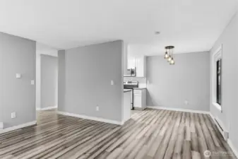 Another living room view showing the dining area and the hallway to the entry and bedrooms.