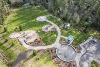 Set within a backdrop of towering evergreens, these thoughtfully designed community play spaces blend open lawns, modern playground structures, splash features, and shaded gathering areas into one cohesive outdoor experience. Winding paths connect each element, inviting movement, connection, and quiet moments in nature.  Beautifully integrated into the landscape, this is everyday recreation — grounded, welcoming, and distinctly Northwest.