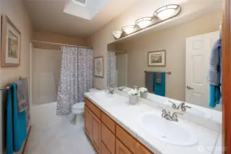 Upper full bathroom w/tiled countertops/backsplash, dual vanities & skylight.