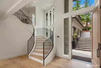 Grand entryway with soaring ceilings, sweeping staircase, and walls of windows that fill the space with natural light.