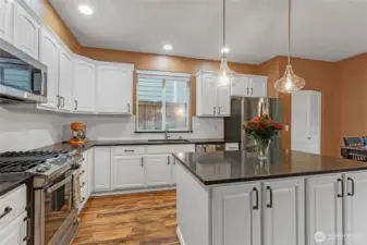 A masterpiece of design, this kitchen boasts crisp white cabinetry, sleek quartz countertops, and a modern hexagonal tile backsplash. The oversized center island offers extra prep space and a breakfast bar for casual dining.