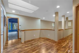 The upper-level landing features an elegant open-rail banister that maintains the home’s airy, connected feel. This spacious transition area offers easy access to the private quarters while overlooking the grand architectural details of the main floor.