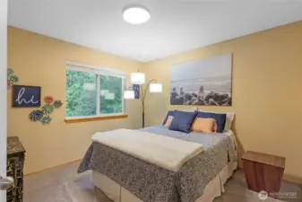 This bright and inviting guest bedroom features oversized windows that frame tranquil views of the surrounding greenery. With high-quality carpeting and neutral designer paint, it’s a versatile space perfect for a nursery, guest suite, or a quiet home office.