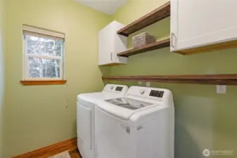 The dedicated laundry room is a model of efficiency, complete with built-in cabinetry for organization, a convenient folding counter, and updated appliances.