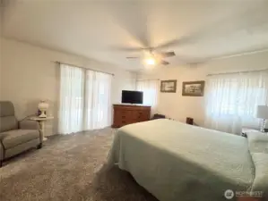 Primary bedroom features sliding doors that open to a comfortable outdoor seating area, perfect for relaxation and enjoying the fresh air.