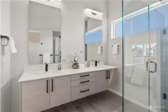 Elegant bathroom with double vanities, sleek finishes, and a walk-in glass shower.