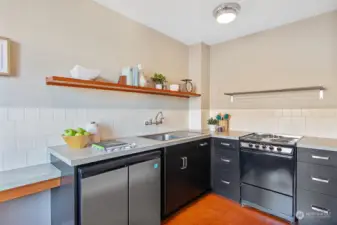 The kitchen has been remolded with efficient space & countertops, an under-counter refrigerator/freezer, a tiled backsplash, open shelving & an eating area.