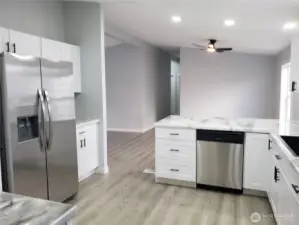 Opposite View of the Very Spacious All New Kitchen with New White Cabinets, Counter Tops, Walk In Pantry, Stainless Appliances Including Microwave, New Paint, Sink, Faucet, Trim and Vinyl Plank Flooring Looking to the Dining Room.