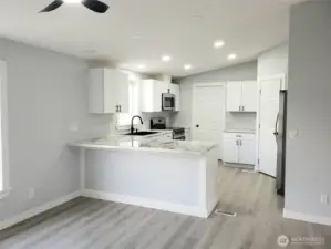 Another View from the Dining Room looking at the Very Spacious All New Kitchen with New White Cabinets, Counter Tops with Breakfast Eating Bar Walk In Pantry, Stainless Appliances Including Microwave, New Paint, Sink, Faucet, Trim and Vinyl Plank Flooring.